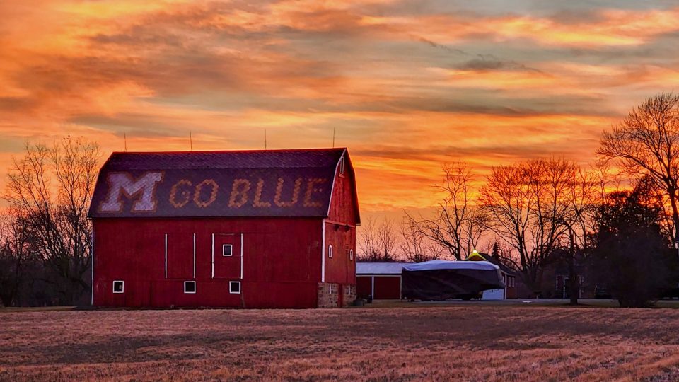 a red barn sitting in the middle of a field